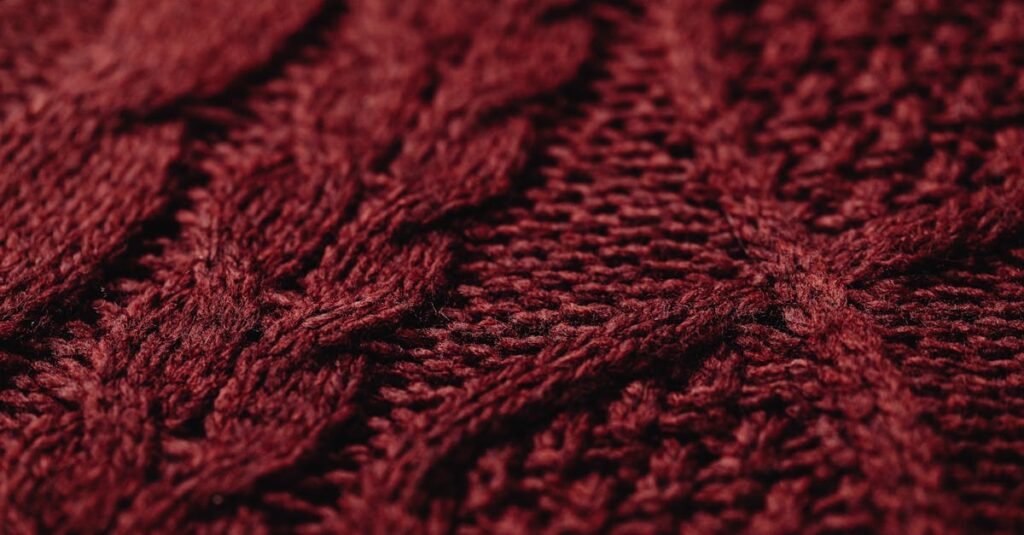 Detailed view of a burgundy knitted textile fabric showcasing intricate patterns and texture.